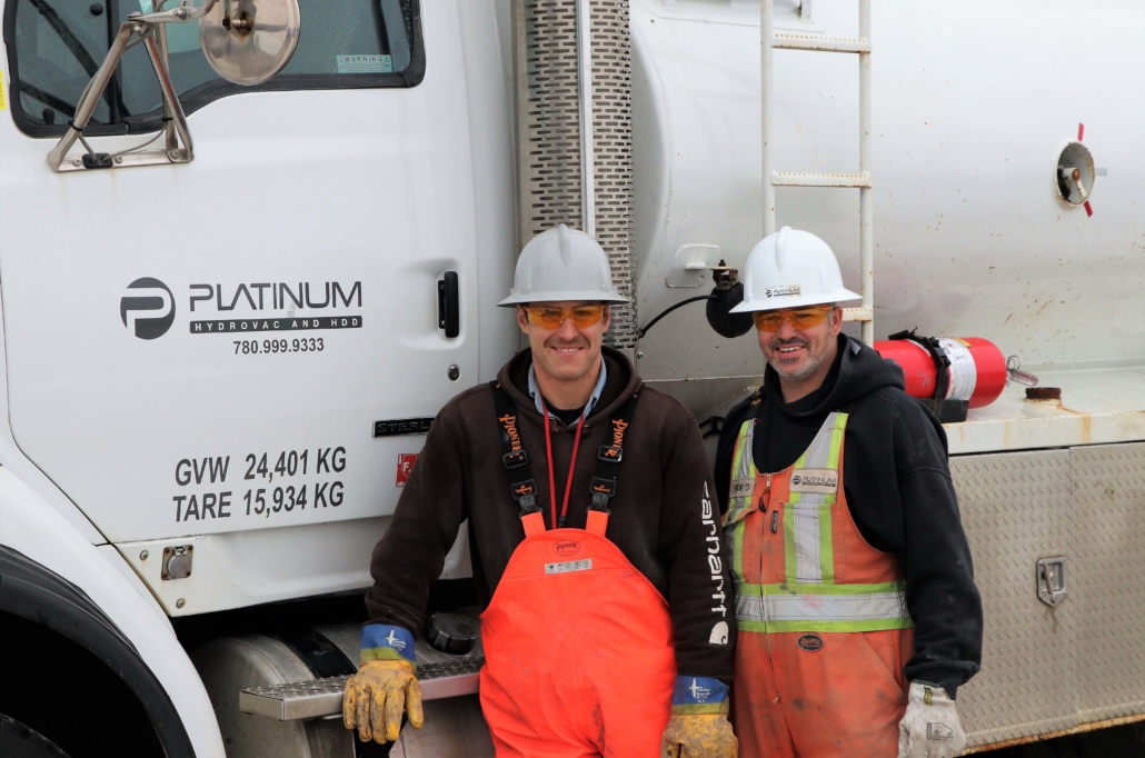 Two platinum employees smiling and standing in front of a platinum truck